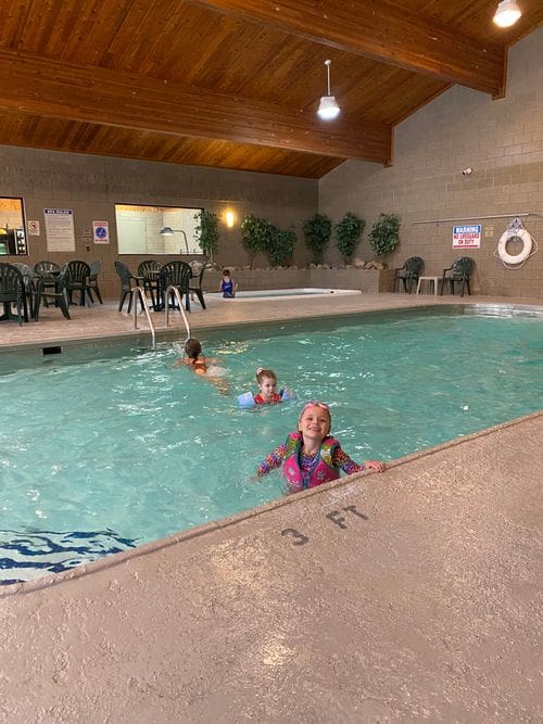 Three kids swim in a large indoor pool at Kavanaugh’s Sylvan Lake Resort.