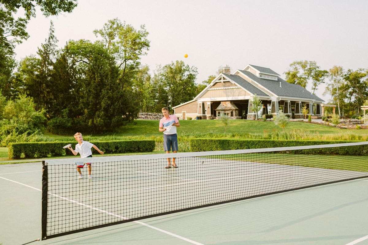 Two kids playing tennis on a summer evening at Madden’s On Gull Lake, one of the best all-inclusive hotels in the United States for families.
