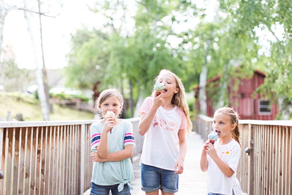 Three kids walk along a beautiful path at Madden’s On Gull Lake, while eating ice cream cones.