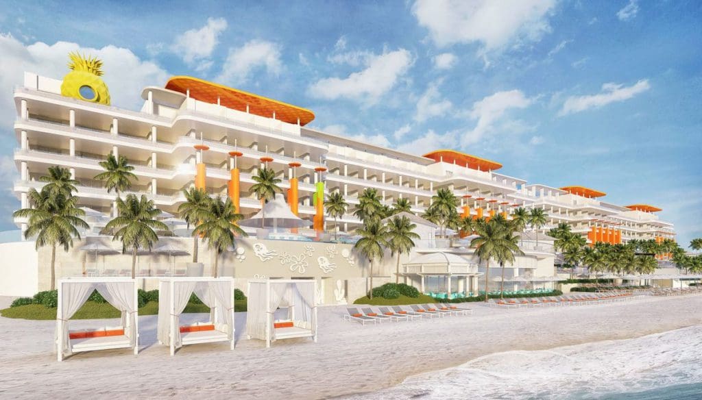 The resort building at Nickelodeon Hotels & Resorts Riviera Maya, featuring white buildings and orange roofs, along the beach, with a canbana awaiting families for a vist.