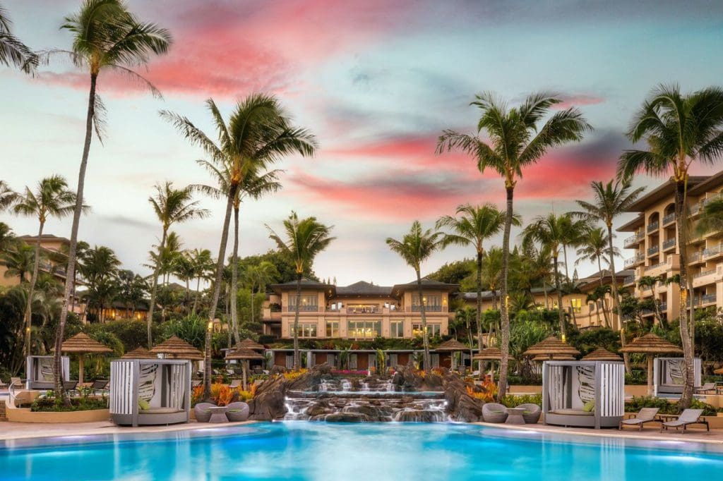 The large pool at The Ritz-Carlton, Kapalua, with resort buildings behind it at sunset.
