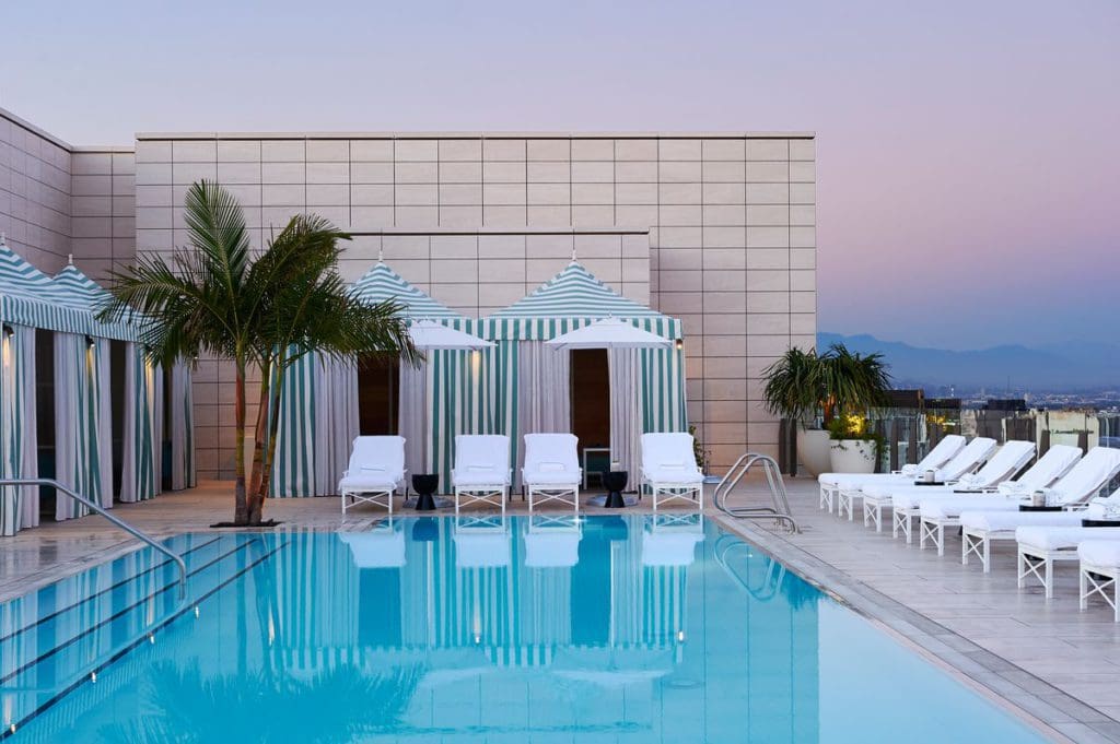 The intimate pool and surrounding white poolside loungers at Waldorf Astoria Beverly Hills.