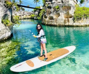 A young girl paddle boards along a small body of water in Xcaret.