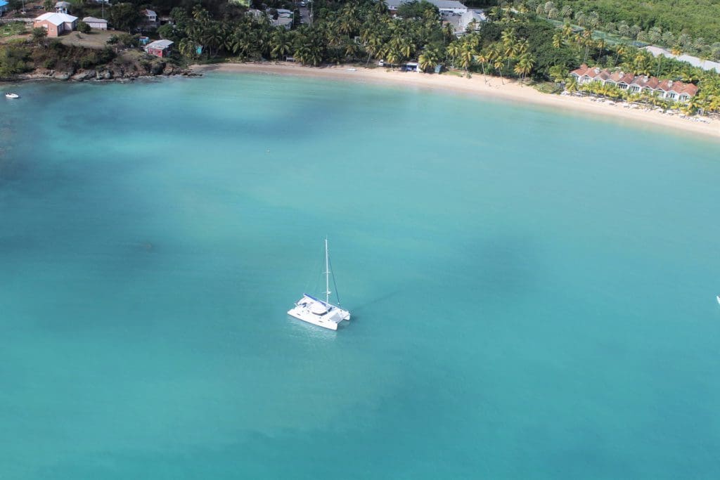 A white catamaran surrounded by crystal blue waters off-shore from Barbados.