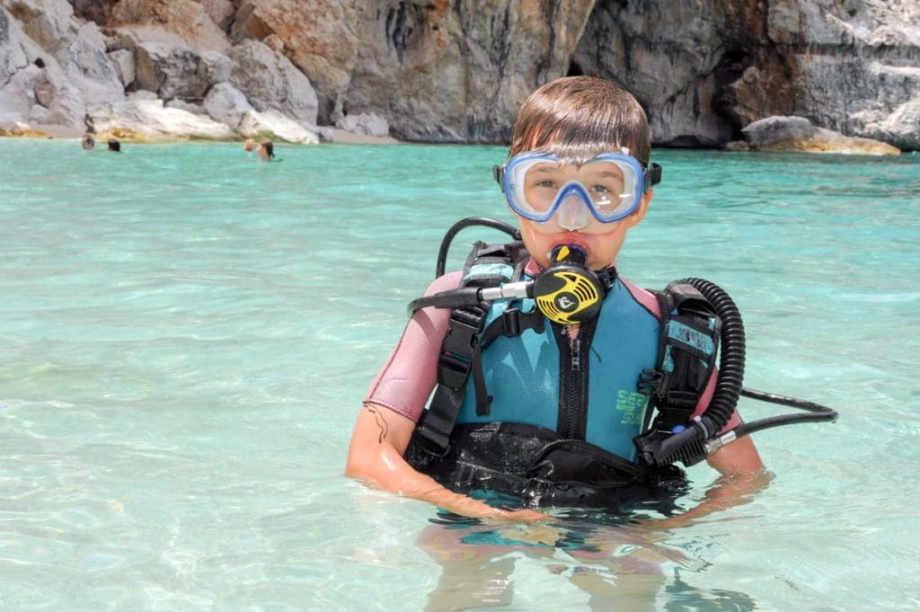 A child discovers scuba diving at Cala Mariolu Beach on Sardinia, one of the best places to visit in Italy with kids.