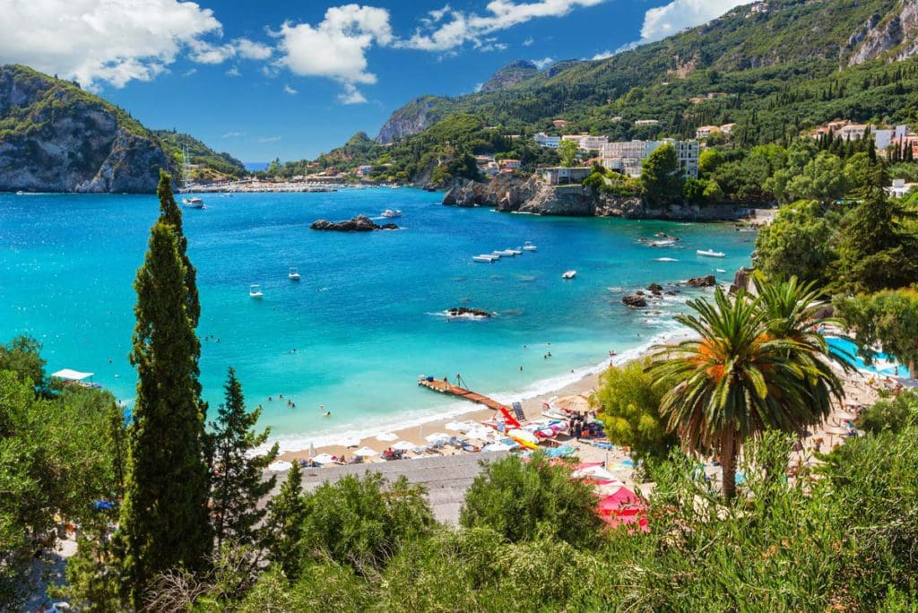 The shoreline in Corfu, featuring a lovely beach that turns to stunning foliage alongside clear blue waters at one of the best Greek islands for families.