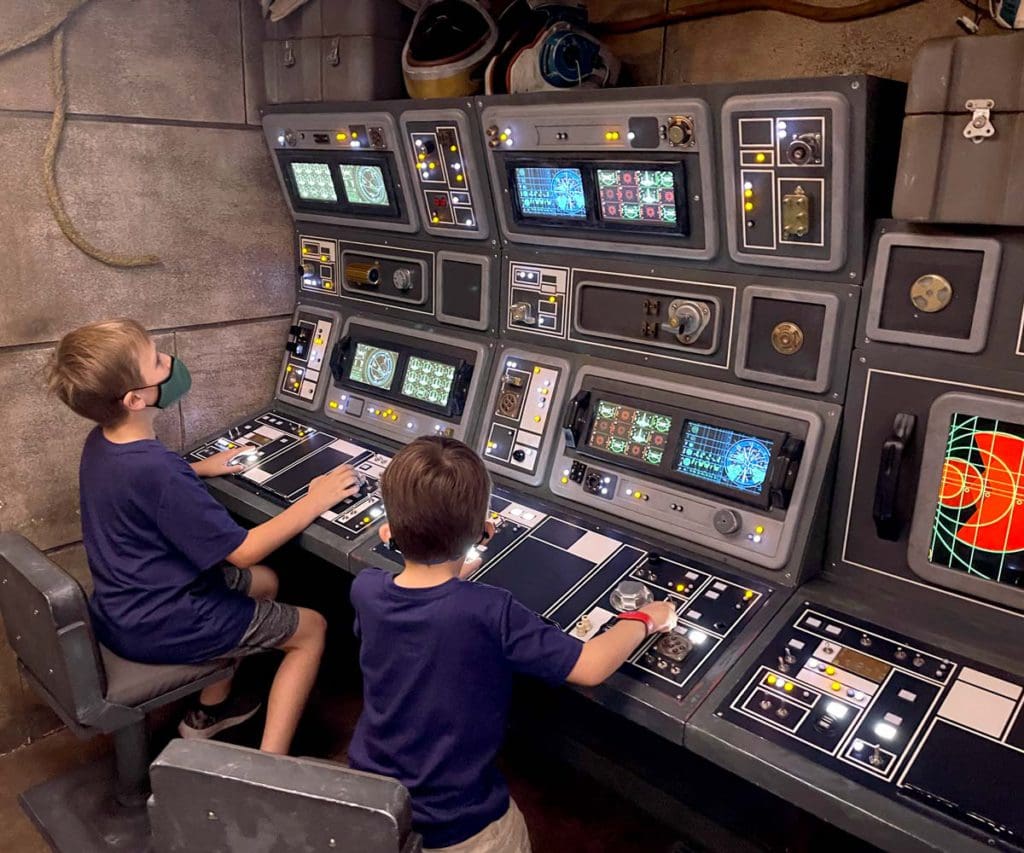 Two kids at the helm of a Star Wars-themed game on a Disney cruise ship.