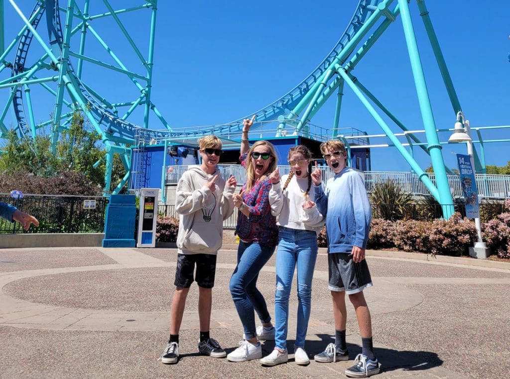 A mom and her three teen triplets stand together excited to go on a roller coaster at SeaWorld San Diego.