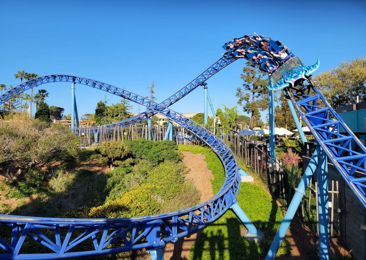 A roller coaster car zooms down the track at SeaWorld San Diego on a sunny day.