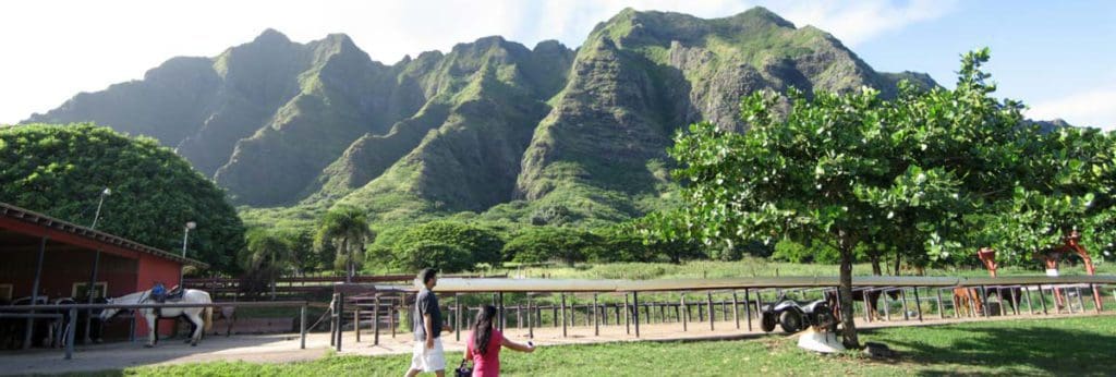 Two people walk across the grounds of Kualoa Ranch, one of the best things to do in Oahu with kids.