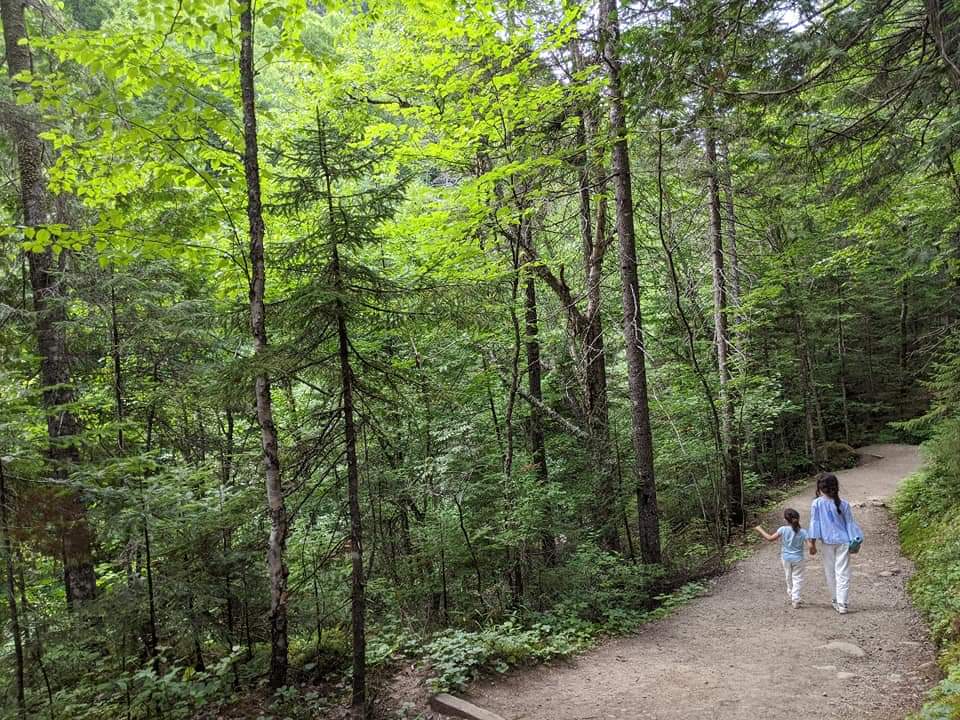 Two girls holding hands walk along a trail in Mont-Tremblant, one of the best vacation destinations for families In Canada.