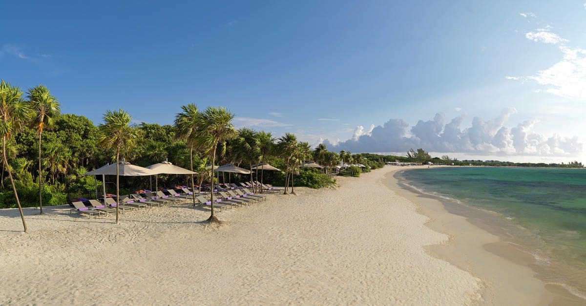 Cabanas set along the beach at Paradisus Playa del Carmen Resort, with clear waters along the shore.
