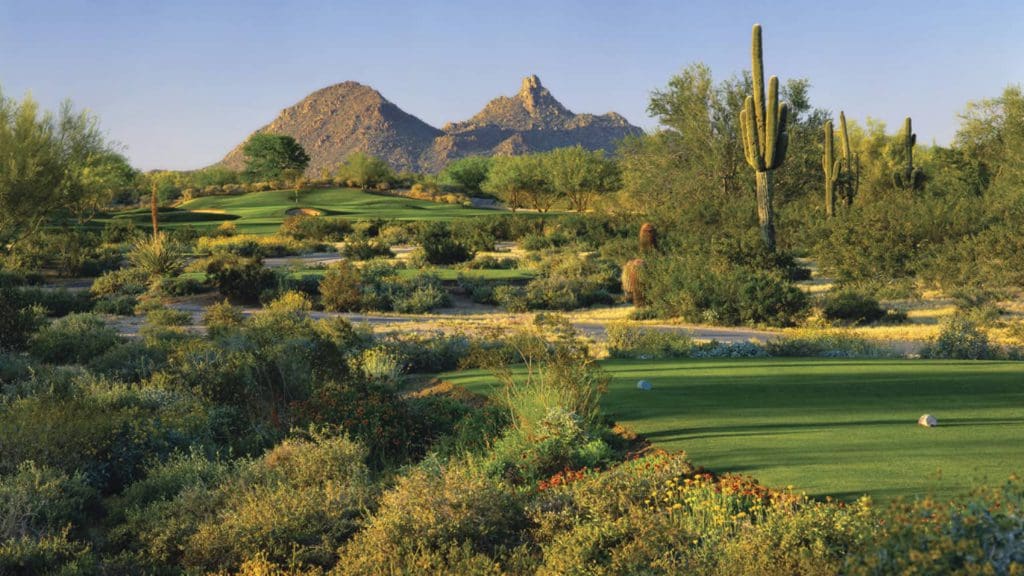 Surrounded by cacti and rolling, verdant hills, view of the outdoor golf course at the Four Seasons Resort Scottsdale, one of the best luxury hotels in the U.S for families.
