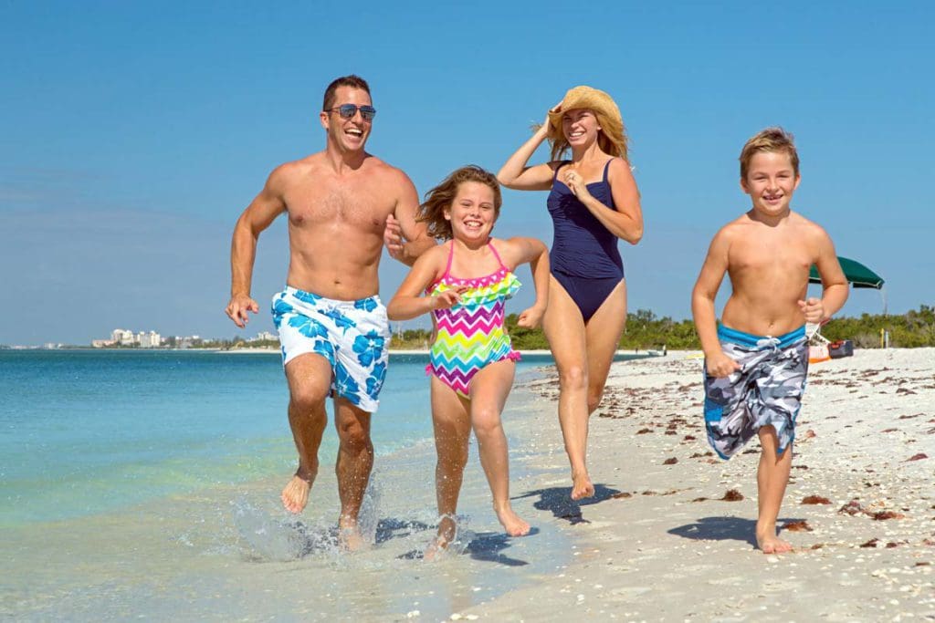 A family of four runs along the beach together at Hyatt Regency Coconut Point Resort and Spa.