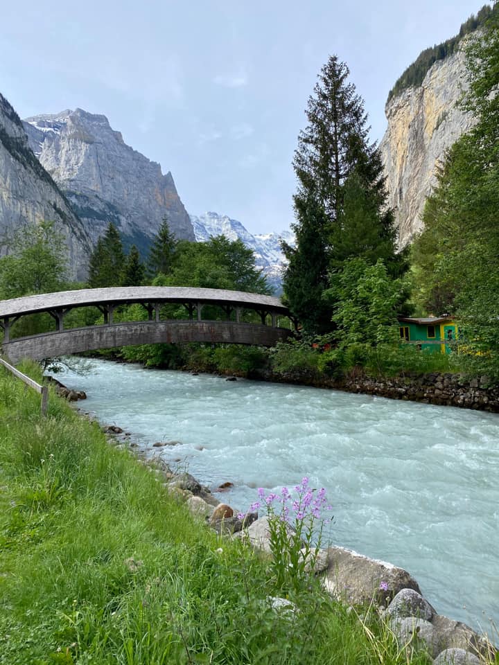 A bridge crosses a river near the mountains of Lauterbrunnen, a must stop on any Switzerland itinerary with kids.