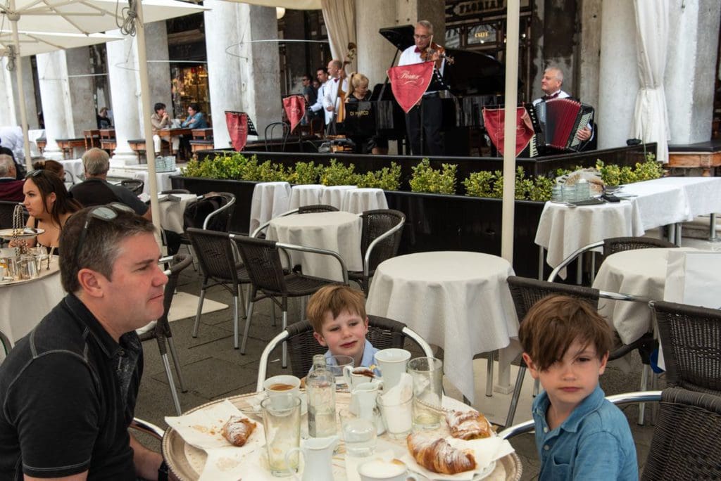 A dad and his two boys enjoy croissants at a local cafe in Venice.