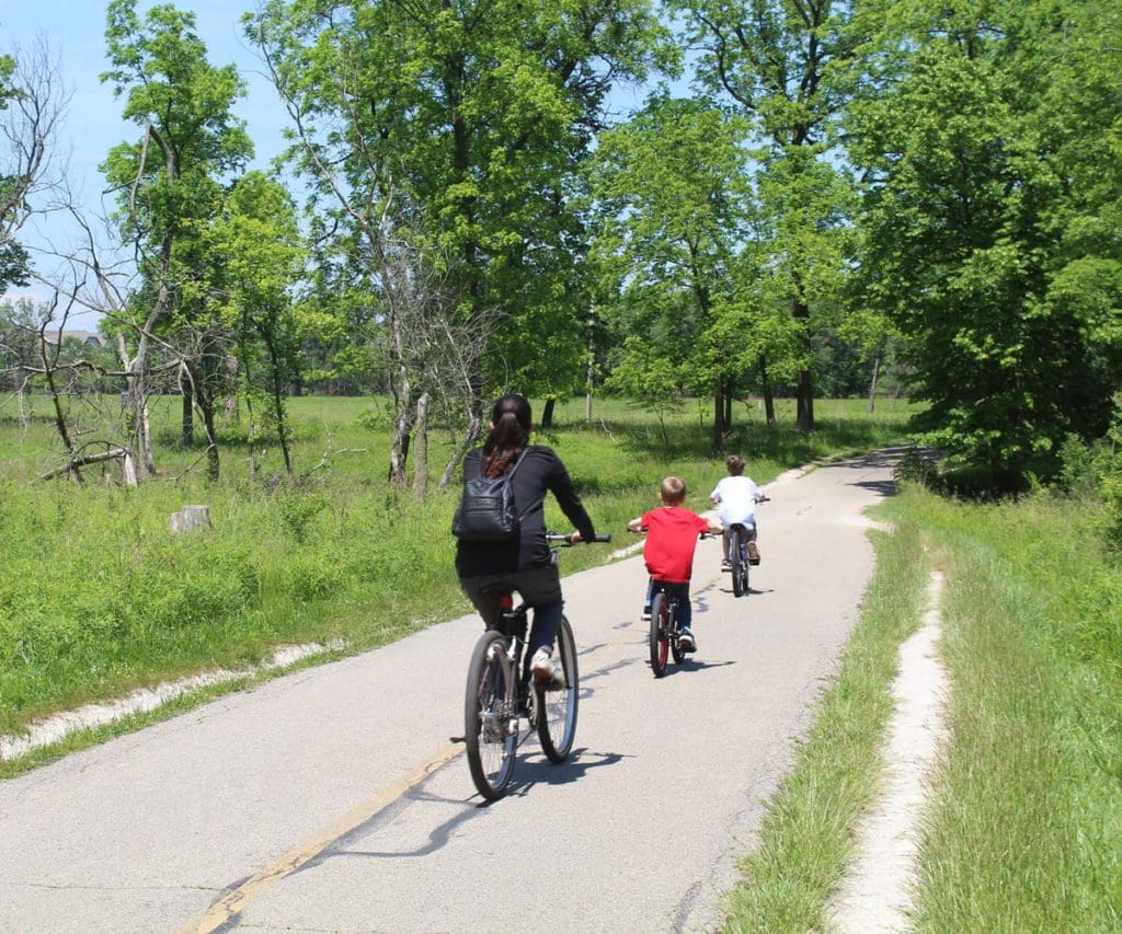 A mother and two sons riding a bike through a grassy path in Northern Illinois.