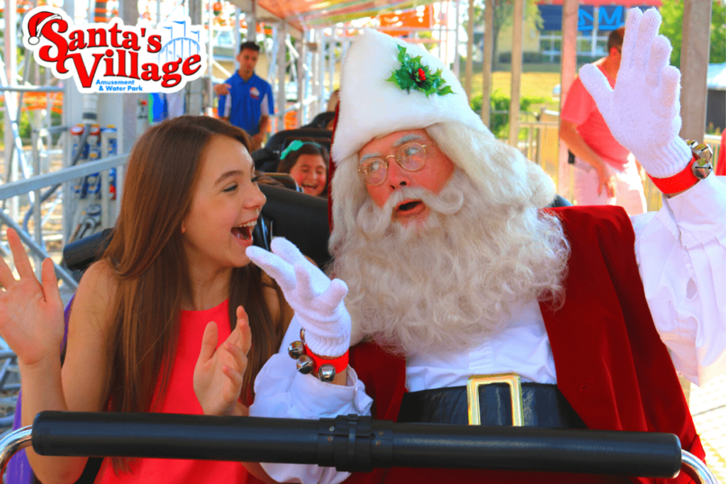 A teen girl and Santa ride together on the lead car of a roller coaster at Santa’s Village Amusement & Water Park.