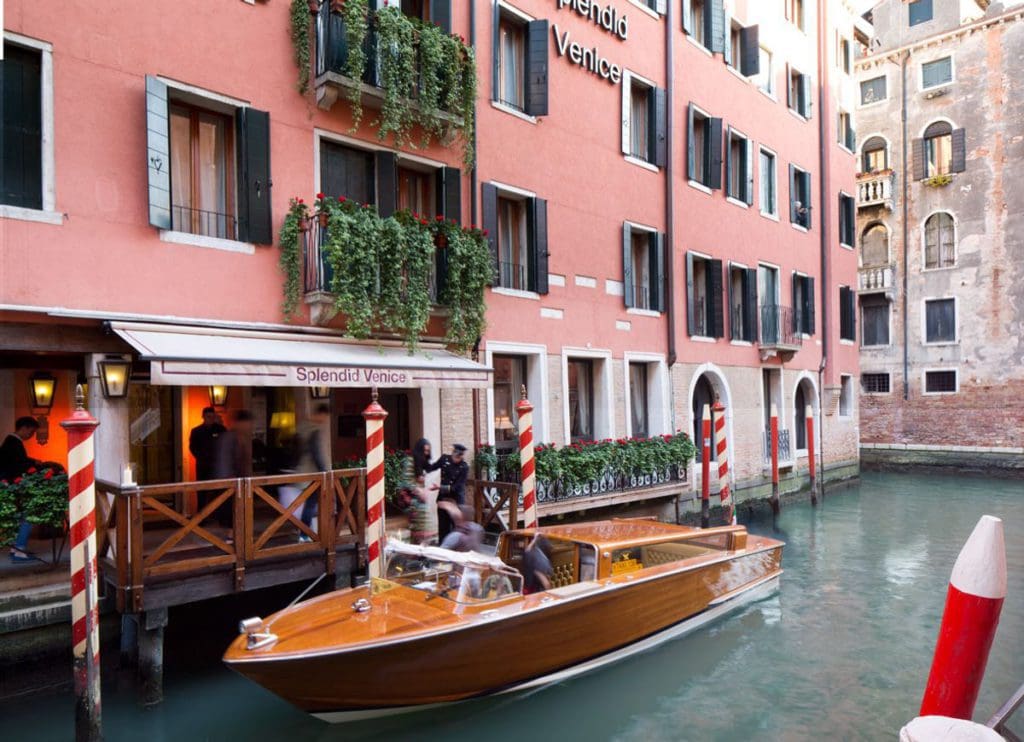 The exterior entrance to Splendid Venice - Starhotels Collezione along the canal, with a gondola waiting outside.