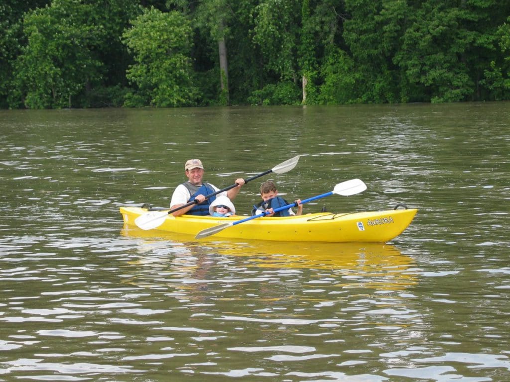 A man canoes along a river near Grafton with his two kids, one of the best places to visit in Southern Illinois for families.