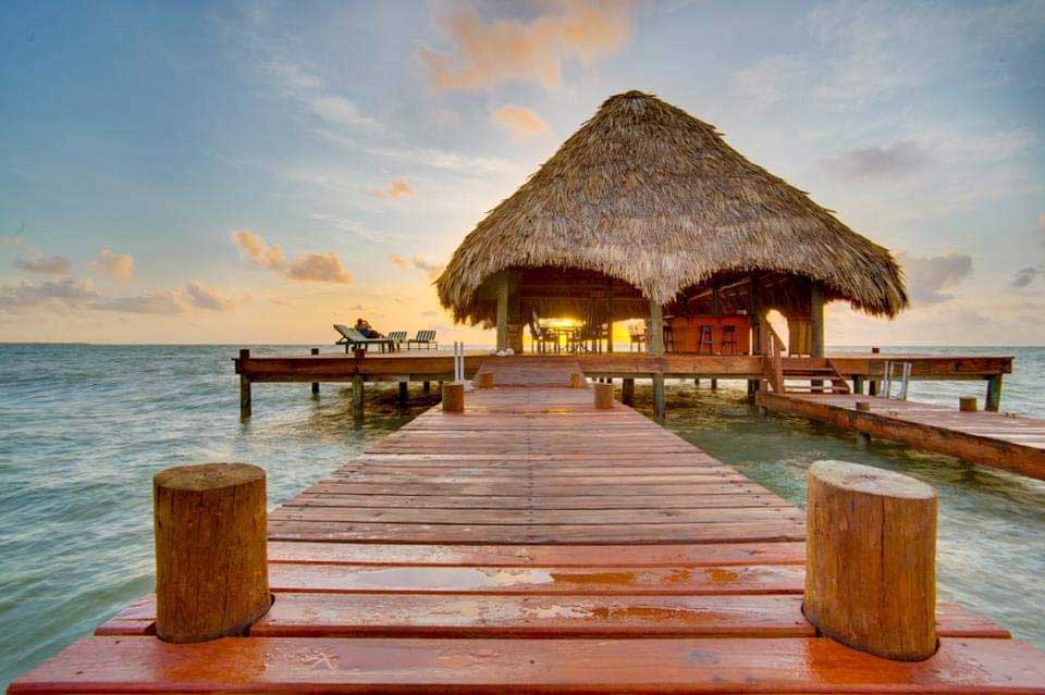 A long pier leading to an overwater restaurant at Robert's Grove Beach Resort, one of the best Belize resorts for a family vacation.