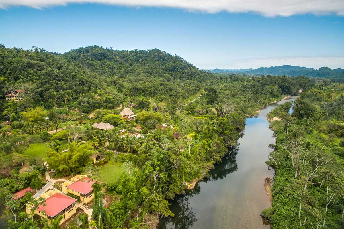 An aerial view of Sleeping Giant Rainforest Lodge, nestled along a river in the Belize rainforest.