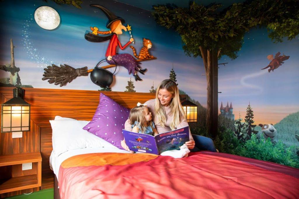 A mom and her young daughter read a book together in the 'Room on the Broom' themed room at the Chessington Safari Hotel.