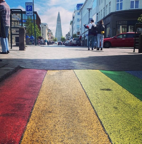 A close up of the iconic rainbow road in Reykjavik, with a straight shot down the road to the building at the end of the street.