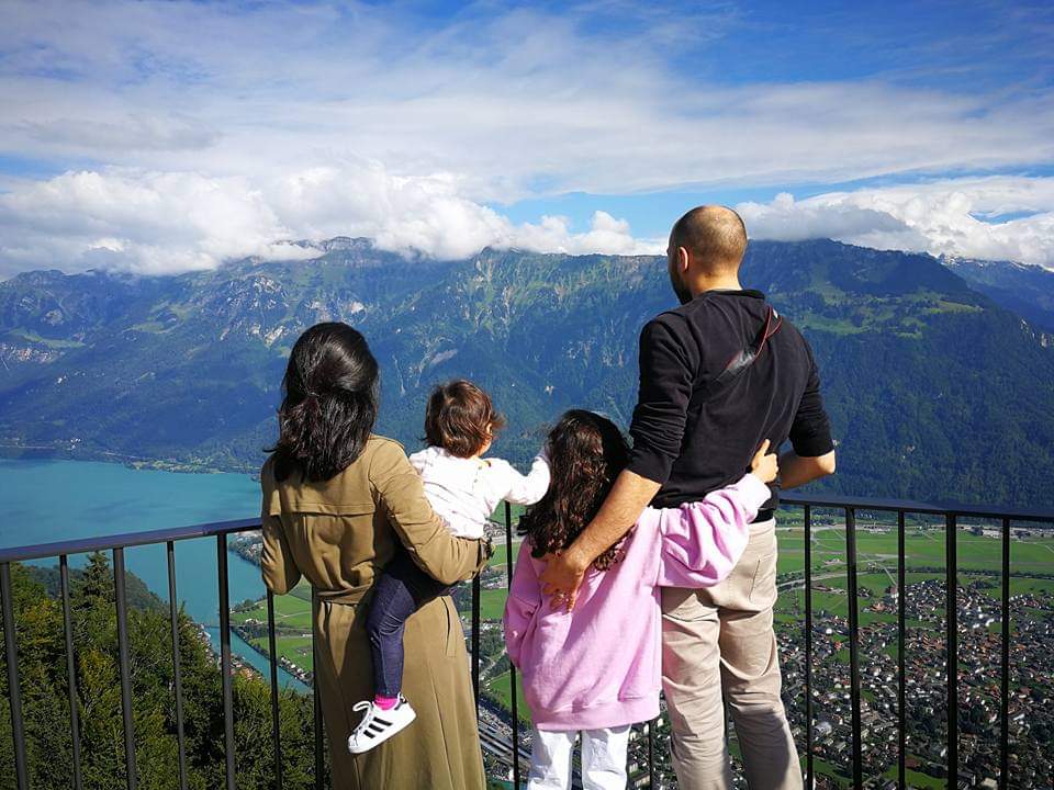 A family of four stands together looking out onto a view the mountains in Switzerland, one of the best all-Inclusive family vacation spots in Europe.