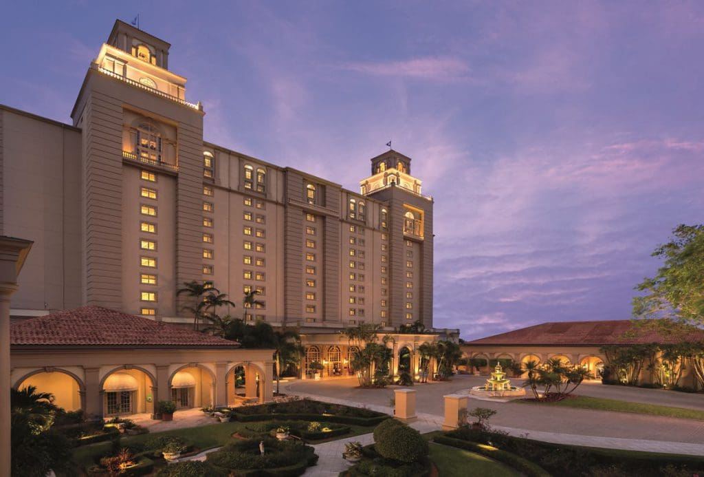 The large resort building front exterior and entrance of The Ritz-Carlton, Naples standing tall at sunset.