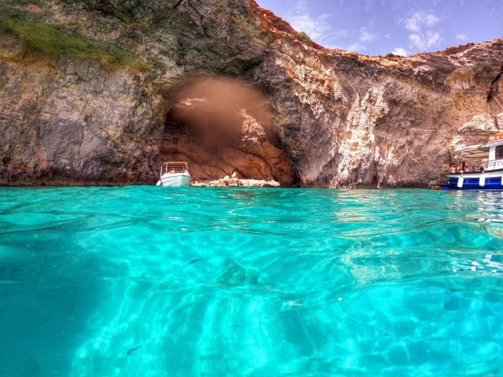 Boats exit the mouth of a sea cave near the Blue Lagoon.