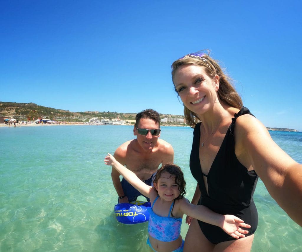 A family of three takes a selfie in the water, while enjoying a family trip to Malta.