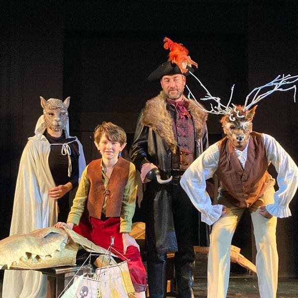 Four people in costume stand on stage during a performance at Teatro San Carlino.