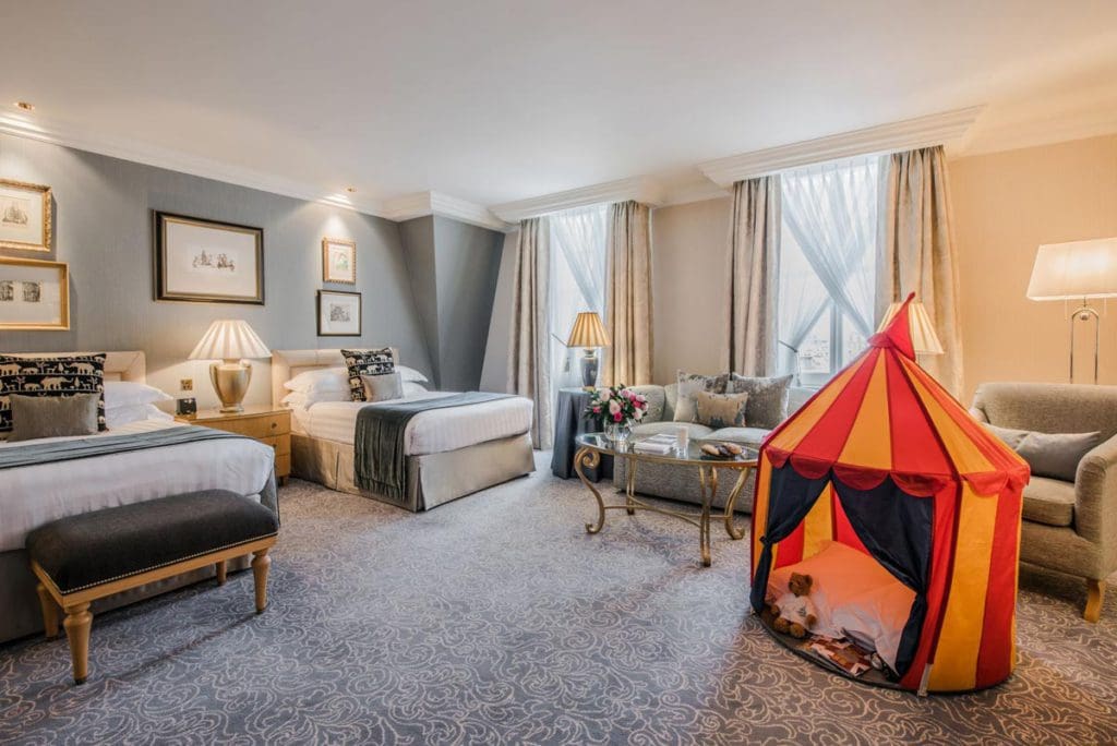 Inside a family room within The Landmark London, featuring two beds, as well as a small tent for kids.