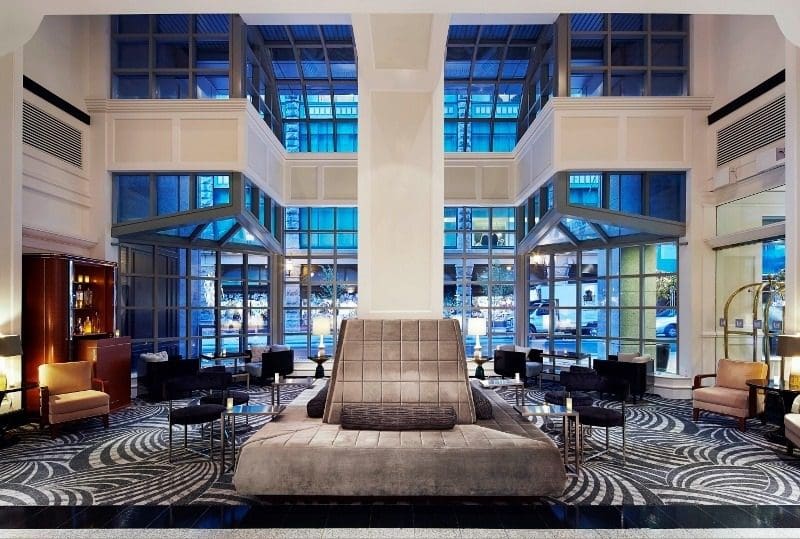 The chic lobby of Vogue Hotel Montreal Downtown, Curio Collection by Hilton, with zebra patterned carpet and cool blue and white hues in the decor.