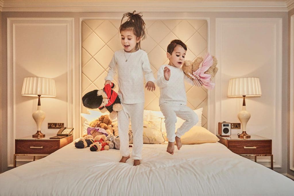 Kids jumping on a hotel bed at London Marriott Hotel Park.