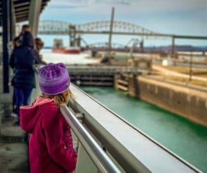 A young girl looks down the Soo Locks toward and oncoming ship moving through the locks.