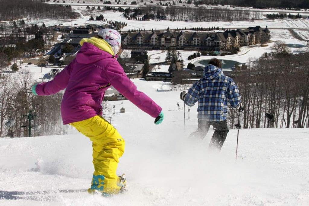A woman and a man ski down a hill at Boyne Mountain Resort during the winter, one of the best places to visit in Michigan with kids.