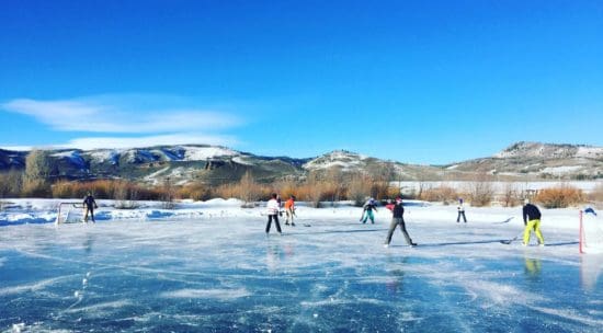 Several people ice skating on a frozen lake on a sunny, winter day at C Lazy U Ranch, one of the best all-inclusive hotels in the United States for families.