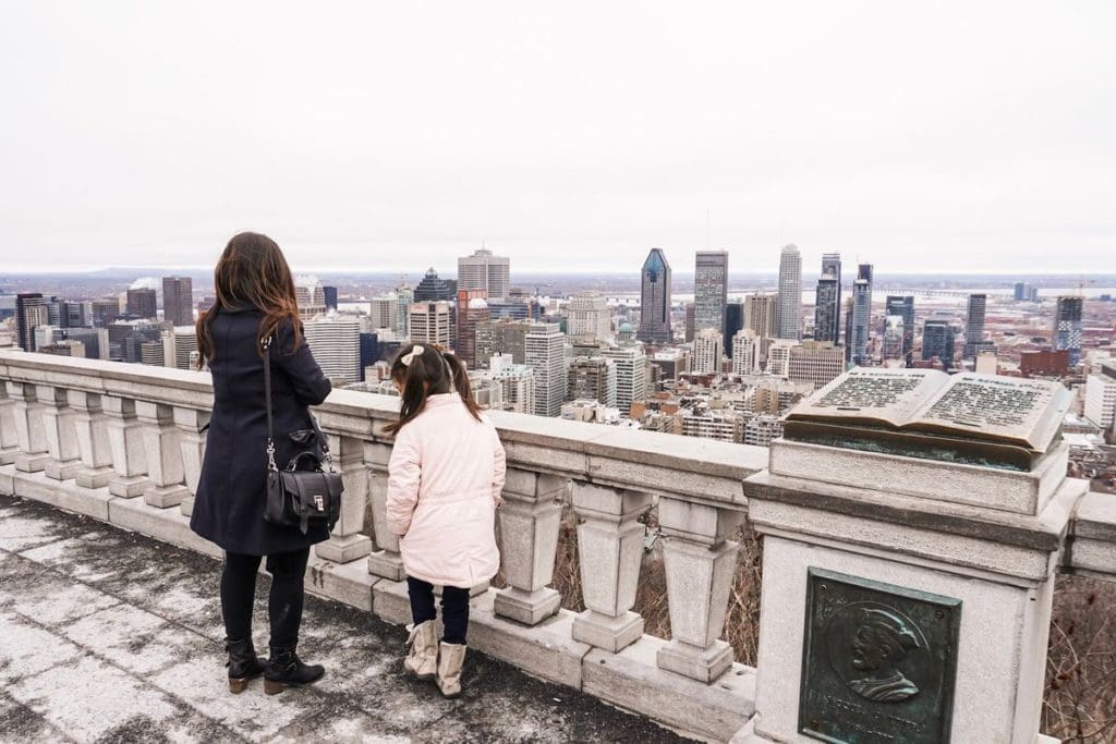 A woman and her daughter look out at a city skyline.