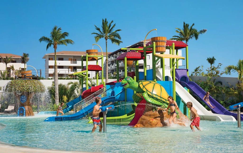Kids splashing and play in the small, on-site water park at Dreams Playa Mujeres Golf & Spa Resort, one of the best hotels in Mexico with large rooms for families.