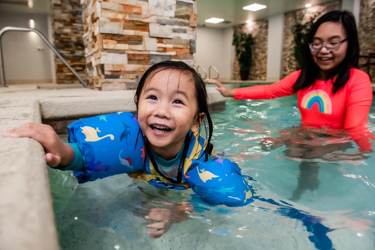 A mom and her young daughter enjoy time together in the indoor pool at Embassy Suites by Hilton Austin Downtown South Congress.