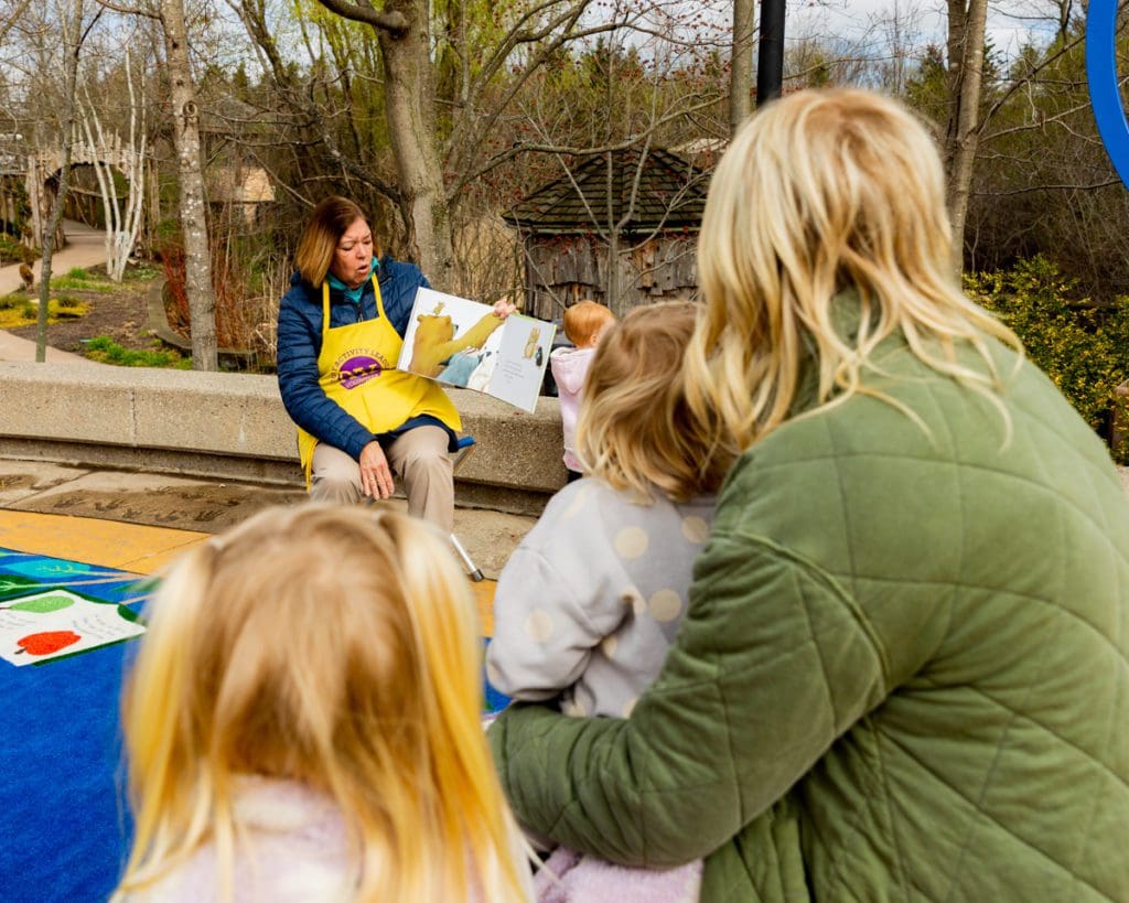 Families gather around for story time in the Children's Garden at Frederik Meijer Gardens & Sculpture Park, one of the best places to visit in Michigan with kids.