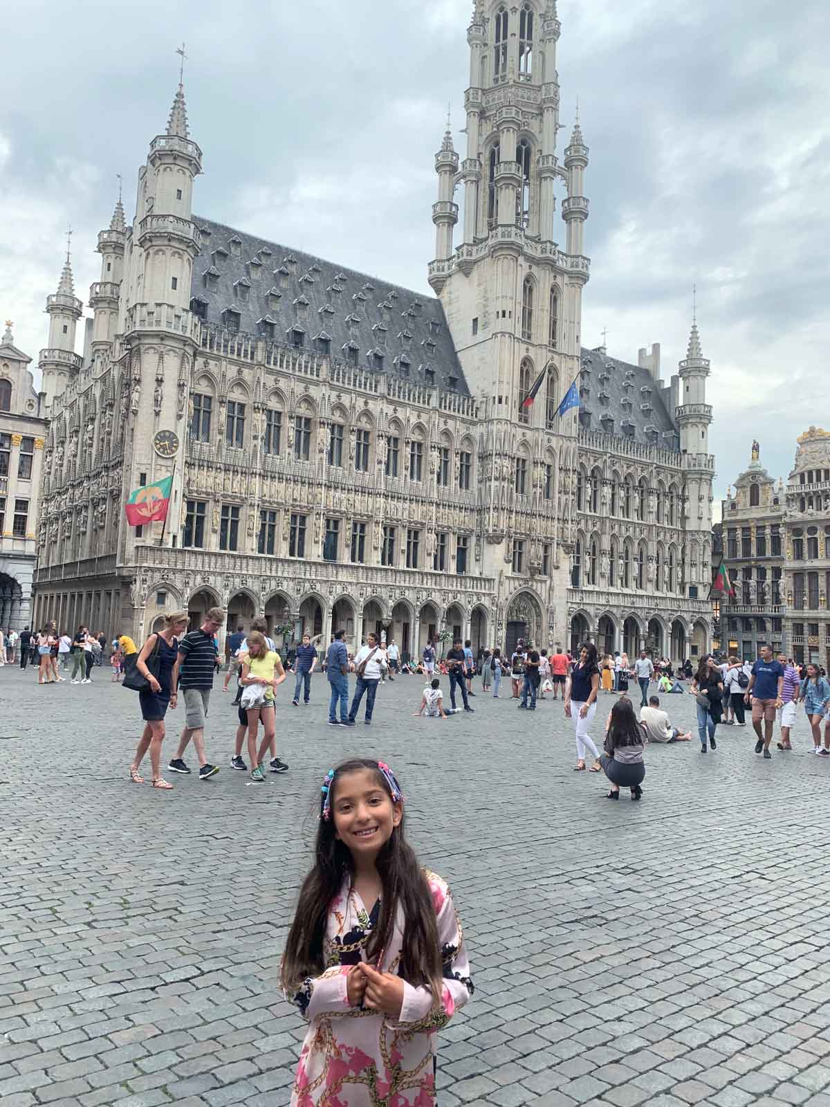 A young girl stands in front of a historic building in Brussels, one of the best places in Belgium for families.