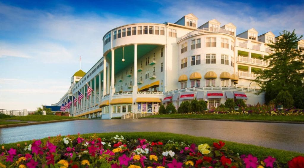 The entrance to the Grand Hotel, flanked with colorful flowers and with American flags hanging along the terrace, in Mackinac Island.