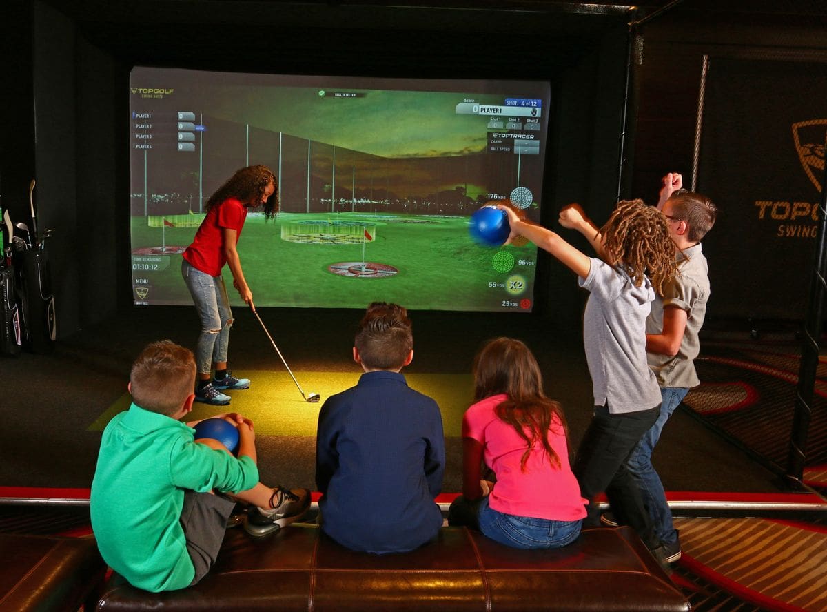 Kids take turns practicing their golf stroke at the Topgolf Swing Suite in Hilton Austin.