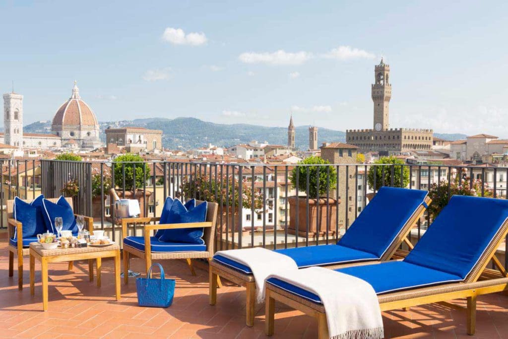 Blue loungers await guests at the rooftop terrace of Hotel Lungarno, with a sweeping view of Florence, including the iconic Duomo, learning where to stay is an important part of knowing all about Italy with kids.