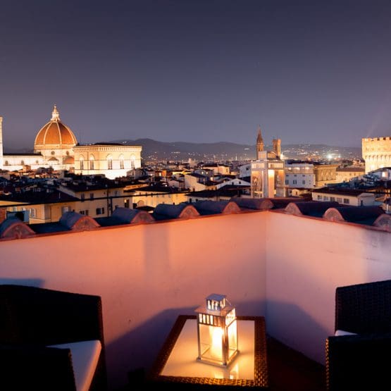 The rooftop of Hotel Torre Guelfa, with a lantern on the cafe table, and a view of Florence at night.