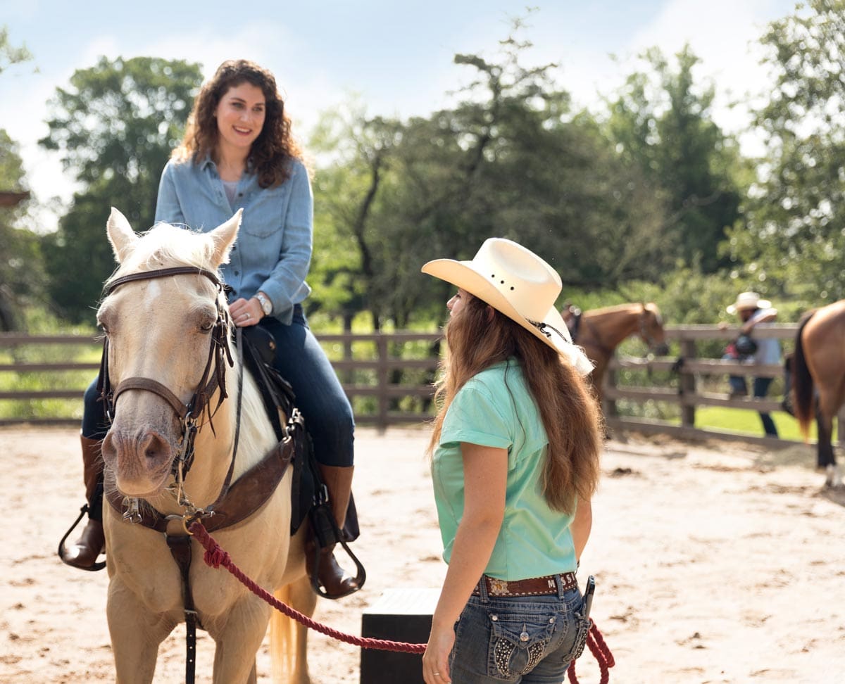 A staff member leads a horse, with a guest riding it at Hyatt Lost Pines Resort and Spa, one of the best hotels in Austin for families.