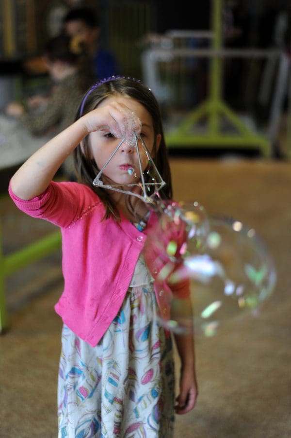A young girl blows bubbles at the Impression 5 Science Center.